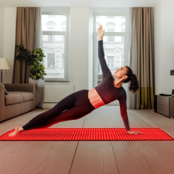 Woman practicing yoga on a red mat in a living room.