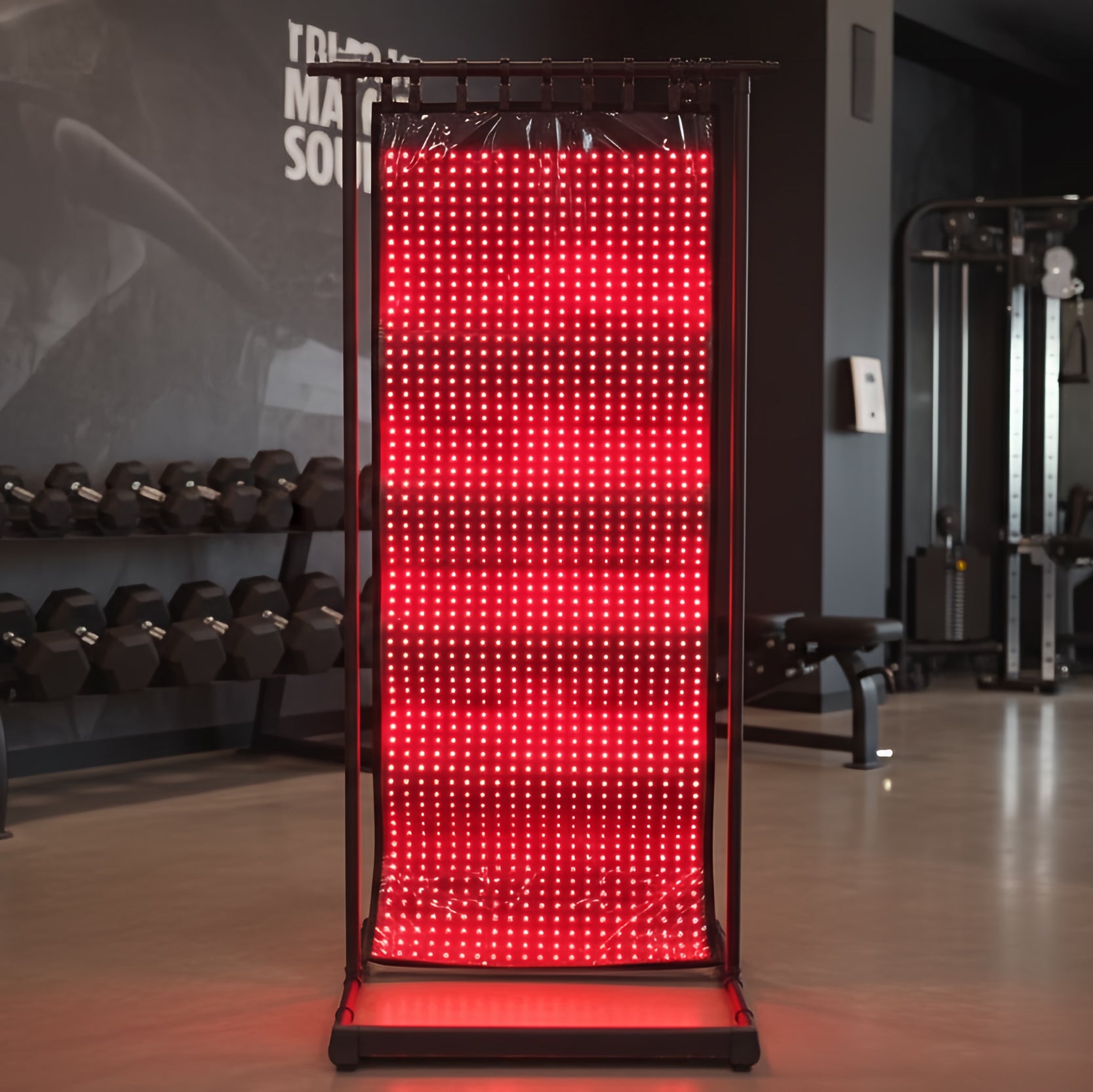 Red LED panel on a stand in a gym setting with weights and equipment in the background.