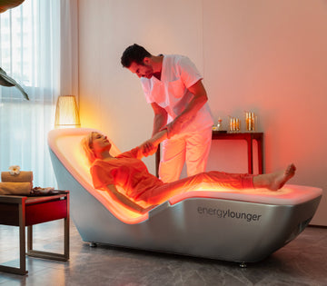 EnergyLounger therapeutic wellness bed with user receiving a relaxing spa treatment under warm ambient lighting