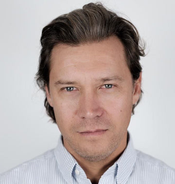 A man in a light striped shirt looking calmly at the camera in a professional.