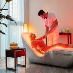 Therapist in a white shirt providing a neck and shoulder massage to a client relaxing in a light-therapy Energy Lounger.